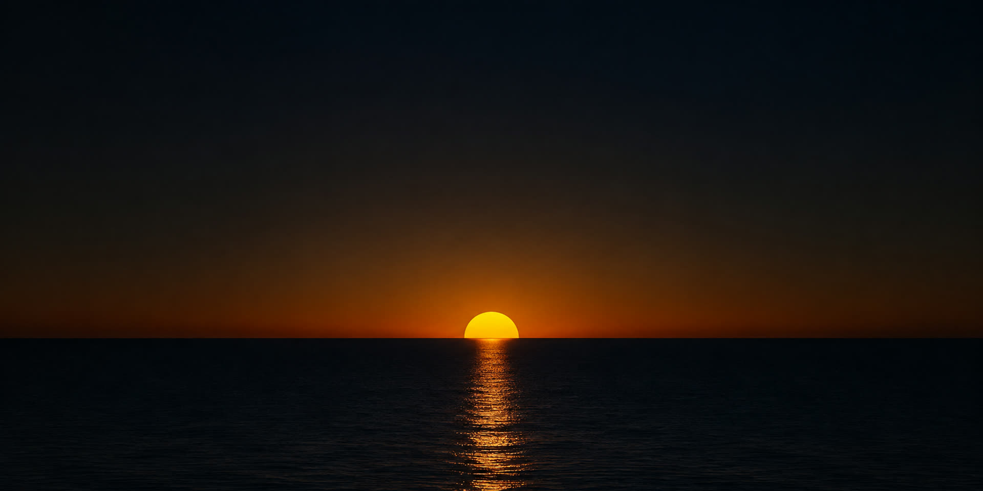 A golden sun sitting exactly on a flat ocean horizon at first light